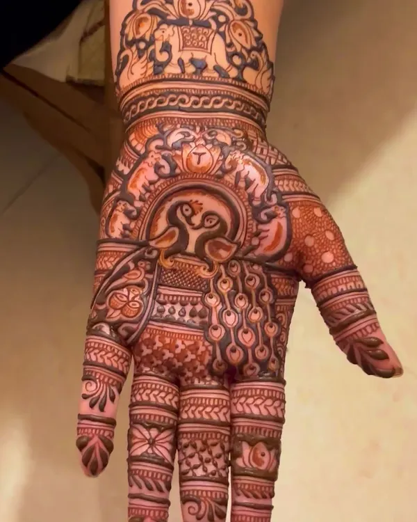 This design is filled with traditional Rajasthani motifs. It features loving peacocks in the center, surrounded by elephant figures at the wrist and detailed finger patterns.