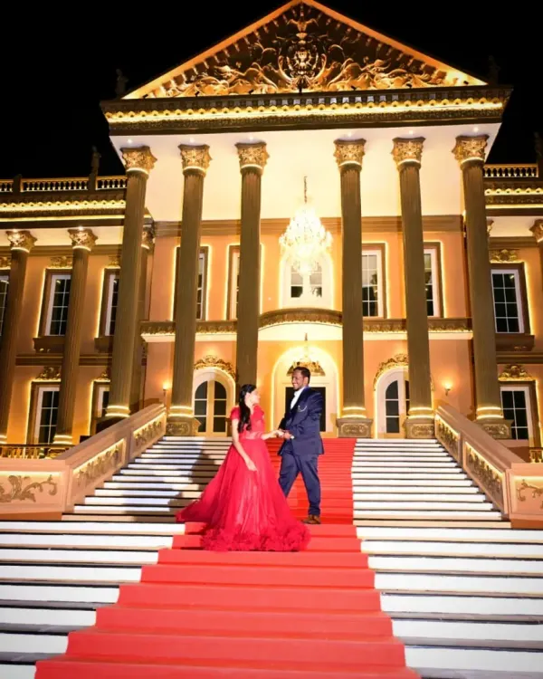 Create a grand, cinematic pre-wedding photo with our red ball gown. This couple's shot on a majestic staircase looks like a scene from a movie.
