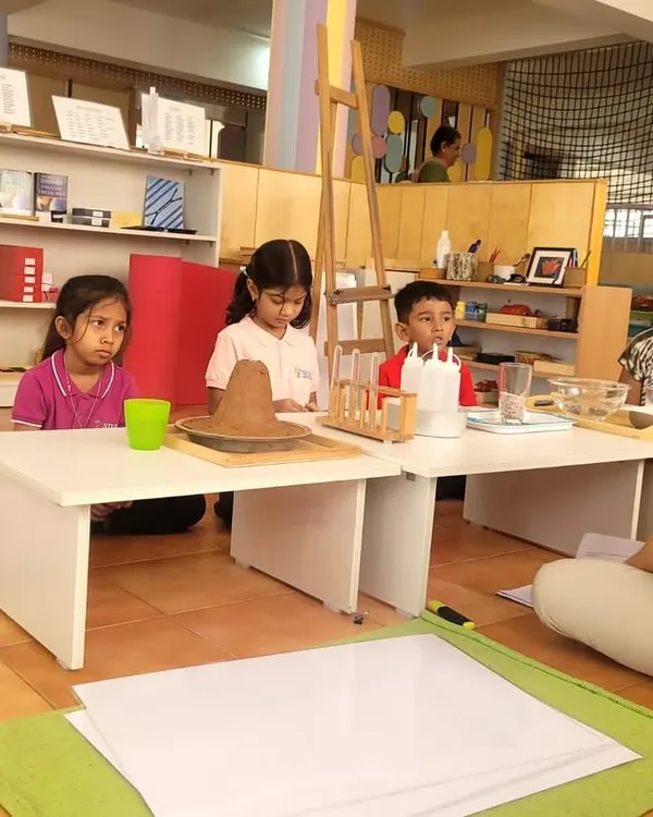 The wonder of science. The children are captivated by a demonstration of a volcano erupting. We use these exciting experiments to introduce concepts from our "Great Stories," like the story of the Earth's formation.