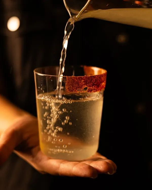 A glimpse into the craft. Here, I am preparing the Amber, a cocktail of bell pepper-infused vodka and pineapple with a hint of cumin tincture. Each pour is a deliberate act of creation.