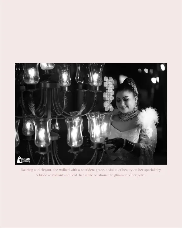 A timeless black and white portrait of the bride, Deepakshi, her smile illuminated by the warm glow of a chandelier at the Grand Imperia.