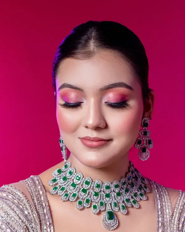 This close-up is designed to put the makeup artistry front and center. With the model's eyes closed, it provides an unobstructed view of the expertly blended pink eyeshadow, long lashes, and smooth foundation finish.