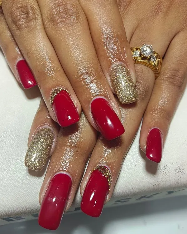 A full view of these stunning bridal nails. The combination of deep red gel polish, gold glitter accent nails, and carefully placed stones at the cuticle creates a look of pure opulence.