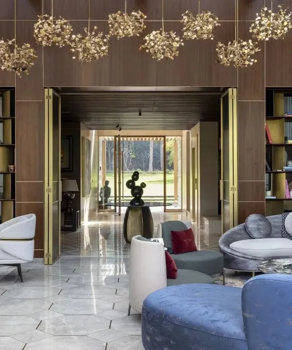 We designed this grand living space in a Vasant Kunj farmhouse to be the heart of the home, blending contemporary luxury with classical details. The custom brass-inlay paneling and bespoke furniture create an atmosphere of refined opulence, with a seamless connection to the lush green landscape outside.