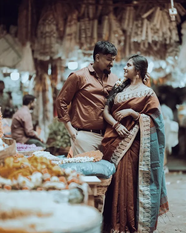 A beautiful moment in a classic Bangalore flower market. The groom-to-be looks on as his partner, dressed in a traditional saree, admires the flowers, creating a timeless, candid scene.