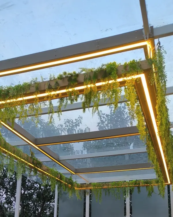 A close-up of a glass pergola I enhanced with hanging artificial creepers and warm LED strip lighting for a magical evening look.