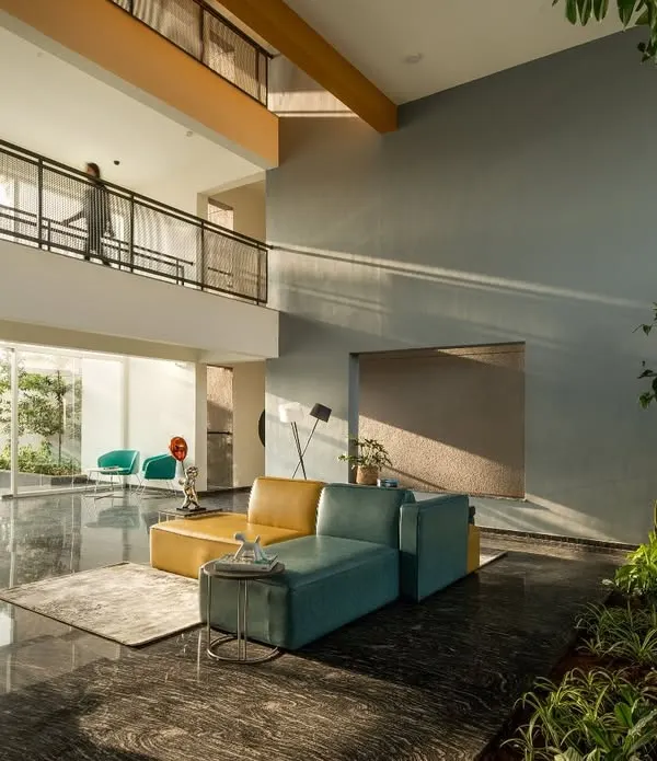 The double-height entrance lobby of "The Treehouse" apartments is filled with natural light, creating a welcoming transition from the city outside. This space is part of a central social core that connects residents vertically through the building.