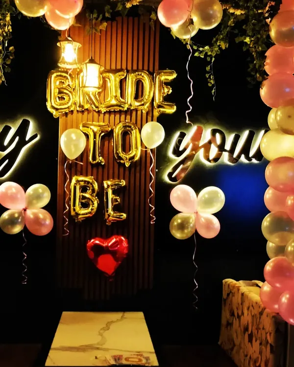 A cozy and intimate "Bride to Be" setup in a restaurant. The gold foil letters and neon signs create a warm and celebratory glow for the future bride.