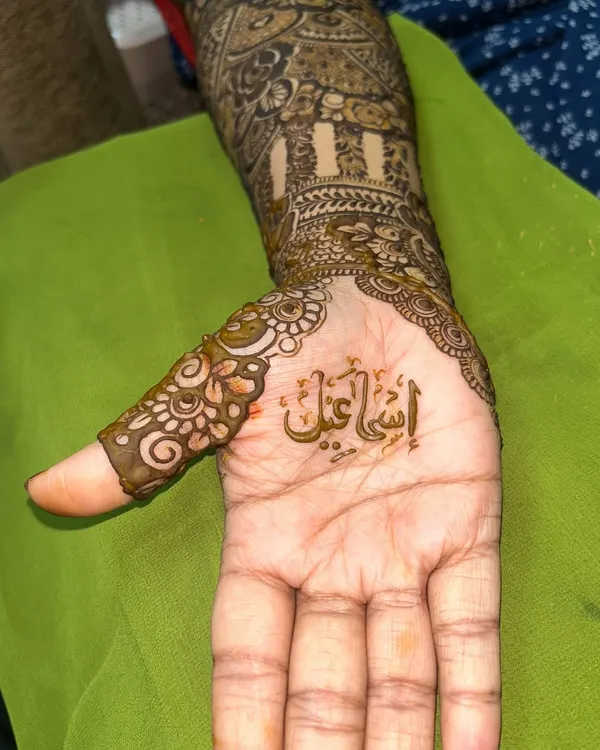 A close-up of a name written in beautiful Arabic calligraphy, nestled in the palm of a bridal design.