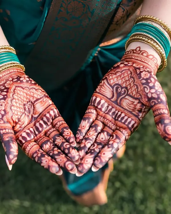 A close-up of the bride's beautiful mehendi, featuring intricate peacock and floral designs. We love capturing this traditional art.