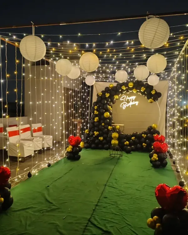 This is a complete cabana-style birthday setup I created on a terrace. It features a custom balloon arch, a neon "Happy Birthday" sign, and is enclosed with fairy lights and paper lanterns to create a magical atmosphere for an evening celebration.