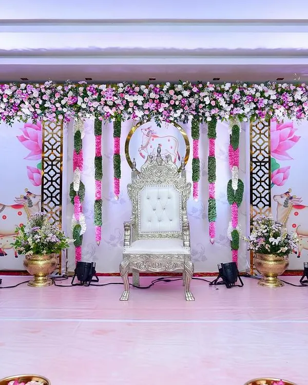 We designed this grand stage for a traditional baby shower, or Seemantham, featuring a regal silver throne for the mom-to-be. The backdrop includes sacred cow and lotus motifs, framed by lush floral garlands in pink and white, creating a truly divine atmosphere.