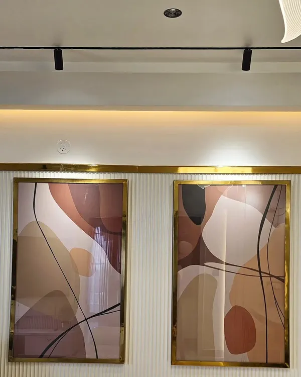 A close-up of a custom diptych I created for a client's home. The artwork features flowing abstract shapes in a warm, neutral palette, elegantly framed in gold to match the interior accents.