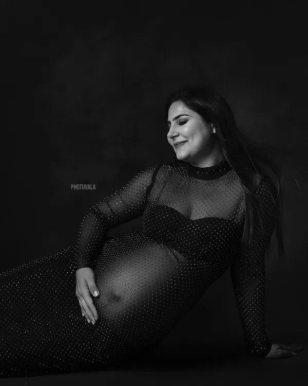A classic black and white portrait celebrating the beautiful curves of pregnancy. This shot, inspired by Bollywood elegance, focuses on the quiet confidence of the mother-to-be.