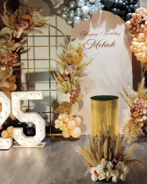 A full view of the stunning boho-chic setup for Mehak's 25th birthday. The decor features large marquee numbers, a custom backdrop, and an elaborate arrangement of balloons and dried pampas grass.