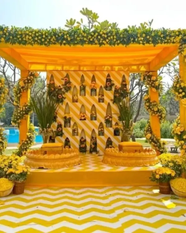 A classic Haldi mandap drenched in yellow. The setup features a beautiful floral frame, traditional seating, and a chevron-patterned floor, all coming together for a picture-perfect ceremony.