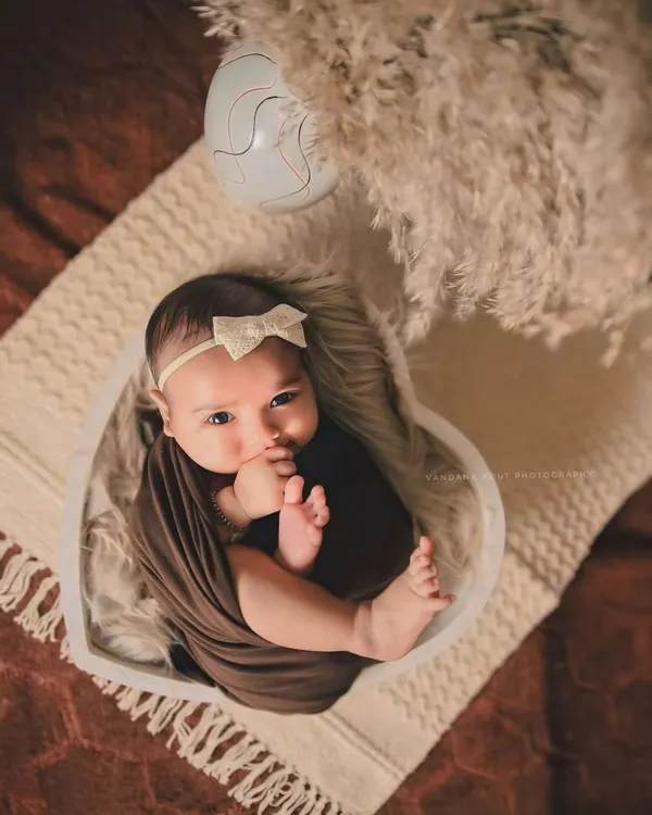 I love capturing those moments when a newborn is awake and curious. This little one, nestled in a heart-shaped bowl with a simple wrap, looks right at the camera, showing off their beautiful, expressive eyes.