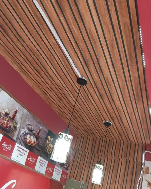 A closer look at the fluted paneling on the ceiling of a cafe. This application draws the eye upward and adds texture and warmth to the entire room, complementing the wall decor.