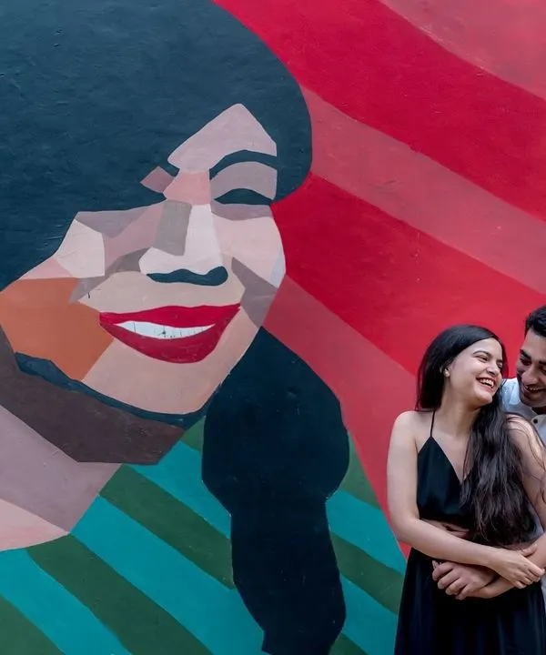 A fun and vibrant shot against a colorful graffiti wall in Delhi. Urban art provides a fantastic, modern backdrop for a themed engagement shoot that is full of personality.