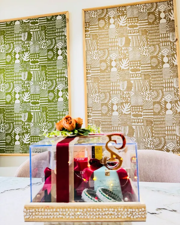A stunning acrylic trousseau box curated with makeup must-haves from brands like Estée Lauder and Bobbi Brown. The box is adorned with a custom initial, traditional bangles, and floral accents.