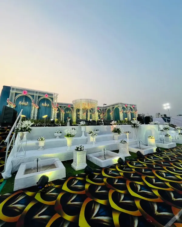 This is the kind of grandeur I love to create. For this royal reception, I designed a massive, multi-level stage with teal and white palace-style arches, a central mandap, and intricate water features to give the couple a truly majestic experience.