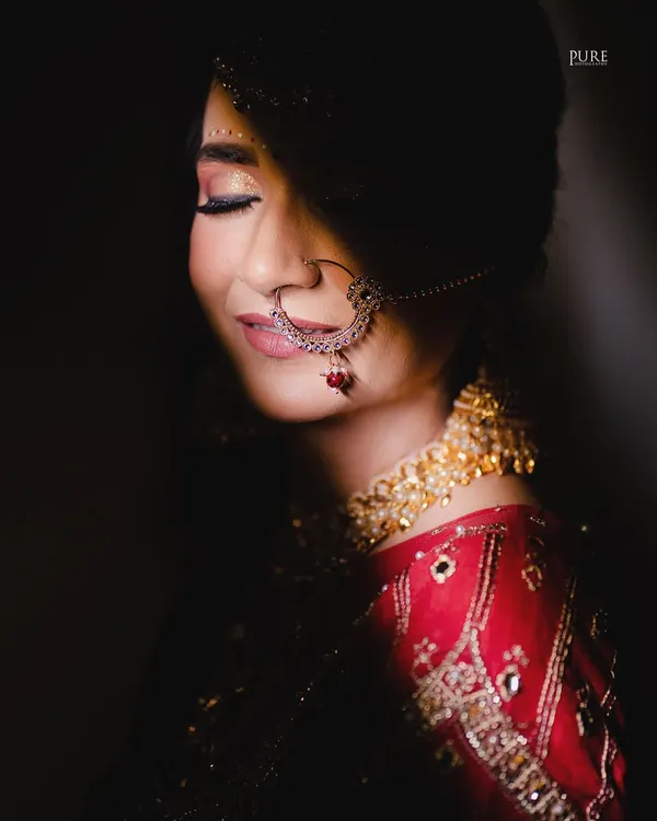 A serene bridal portrait. We used soft lighting to capture this quiet moment of happiness, focusing on the bride's beautiful smile and traditional nath.