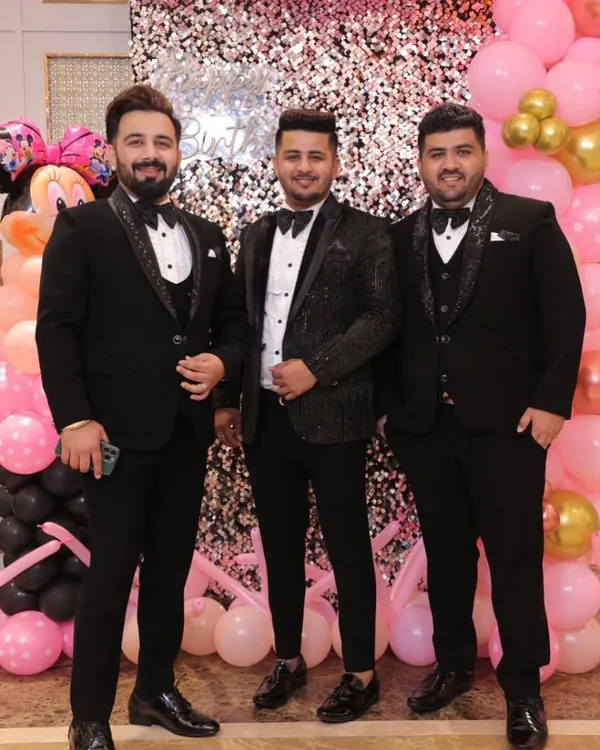 A trio of groomsmen in coordinated black tuxedos. While the base is classic, each tuxedo jacket has a unique texture and lapel design, showcasing individuality within a formal theme.