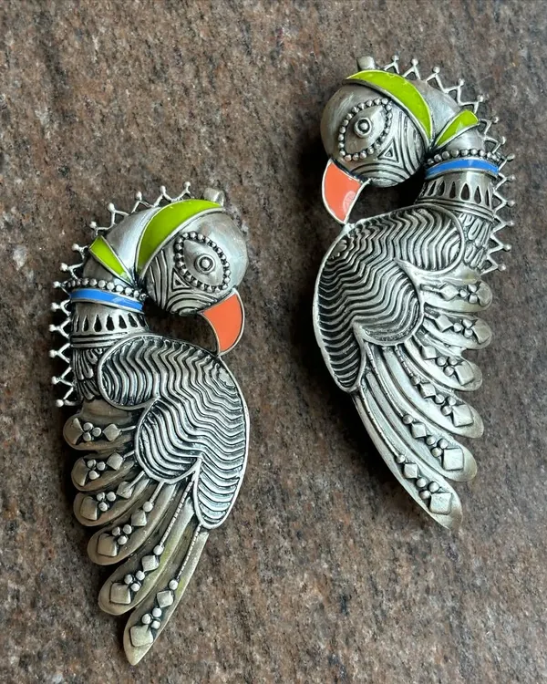 An exclusive pure silver peacock ear cuff. This is not your average earring; it's a statement piece of art that curves gracefully along the ear, with colourful enamel accents on the beak and crest.