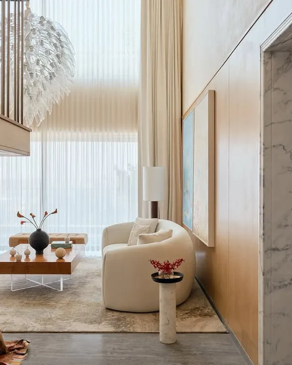 This double-height living room in the NG Penthouse is all about volume and light. The design uses a neutral color scheme, sheer curtains, and reflective surfaces to maximize the sense of openness, making spaciousness the ultimate luxury.