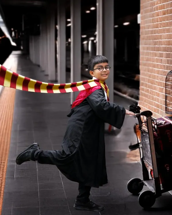A magical Harry Potter themed photoshoot featuring a young boy in a Gryffindor robe pushing a luggage trolley towards a Platform 9¾ sign on a brick wall.
