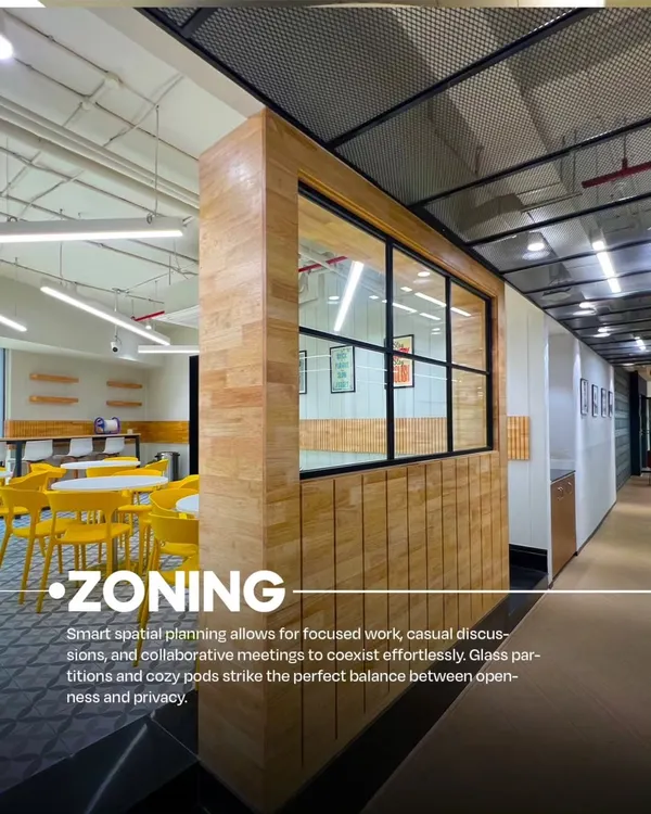 A view of the VentureX coworking space in Gurugram, showcasing our use of zoning. A wooden partition with a window creates a semi-private meeting area next to a more open cafe-style zone with bright yellow chairs.