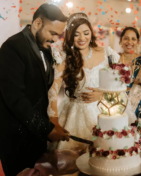 A beautiful moment from a Christian wedding cake-cutting. The bride's makeup is elegant and timeless, mirroring her inner joy.