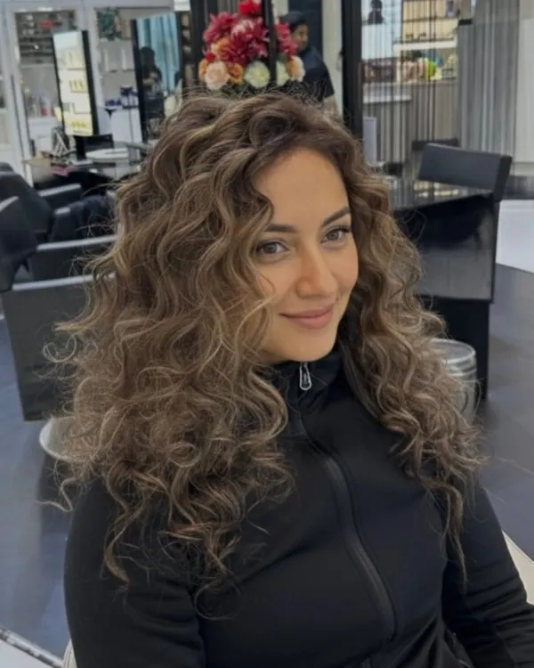 An elegant color transformation on curly hair. The highlights add beautiful dimension and a luxury finish, making each curl stand out.
