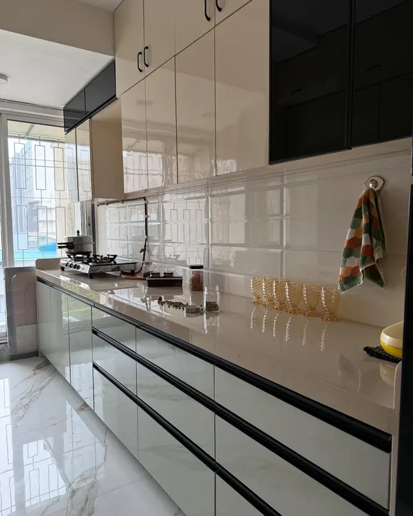 A close-up of a finished modular kitchen. This view highlights the glossy, handleless drawers, the white subway tile backsplash, and the spacious countertop, perfect for meal prep.