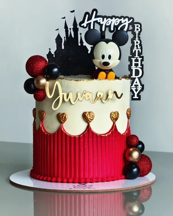 A classic Mickey Mouse theme with a modern twist. This cake features a clean red and white design with a striped buttercream texture, gold hearts, and a silhouette of the Disney castle for a touch of magic.