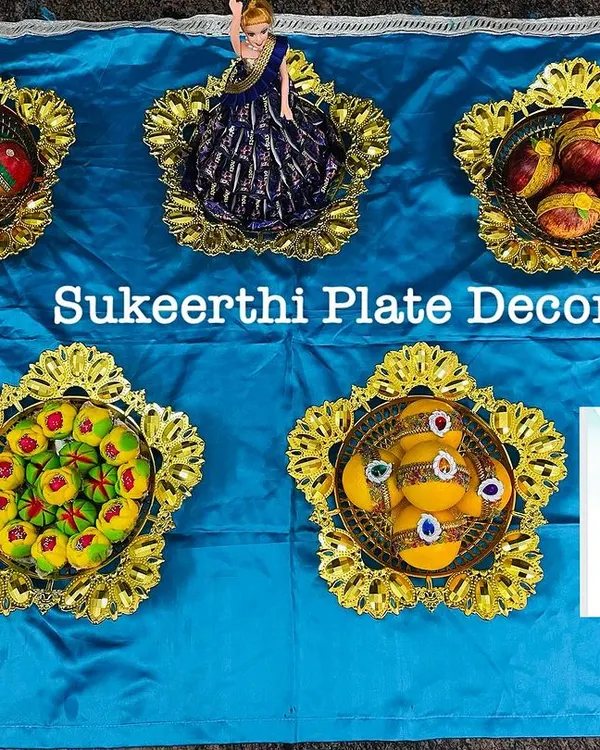 A set of five decorative plates with a blue and gold theme, featuring arranged sweets and a doll centerpiece.
