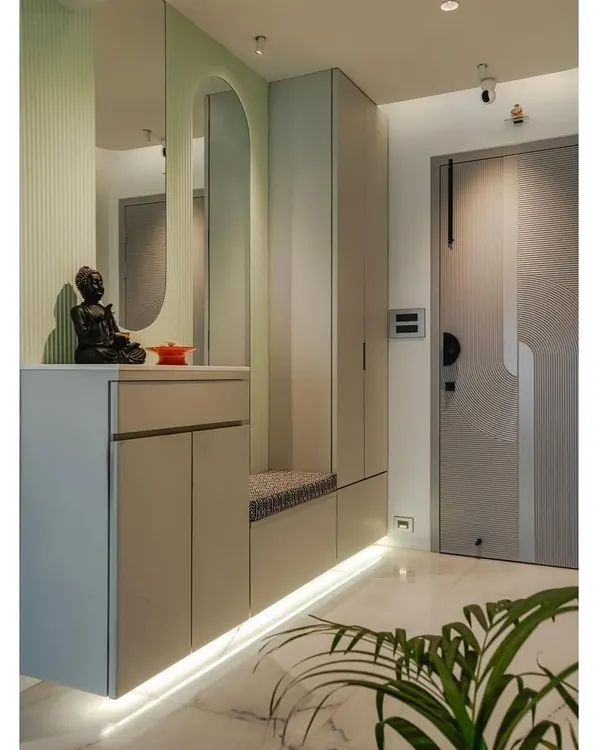I designed this entryway to be highly functional. It features a built-in bench with seating for putting on shoes, concealed storage below, and an arched mirror. The pastel green accent and under-cabinet lighting create a bright and welcoming atmosphere.