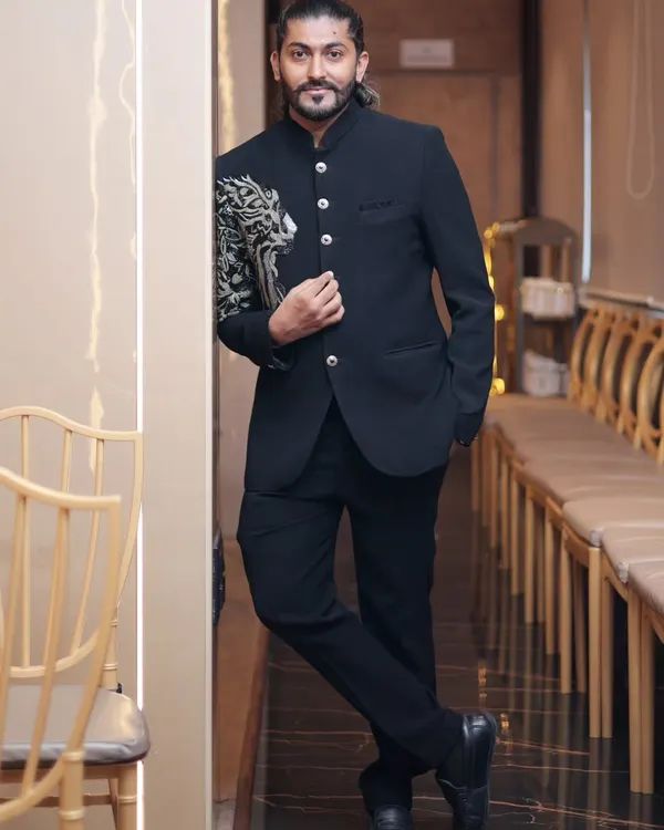 A full-length view of our black Jodhpuri suit on a client. This image shows how the tailored fit and striking shoulder embroidery create a powerful silhouette, perfect for a groom or guest of honor.