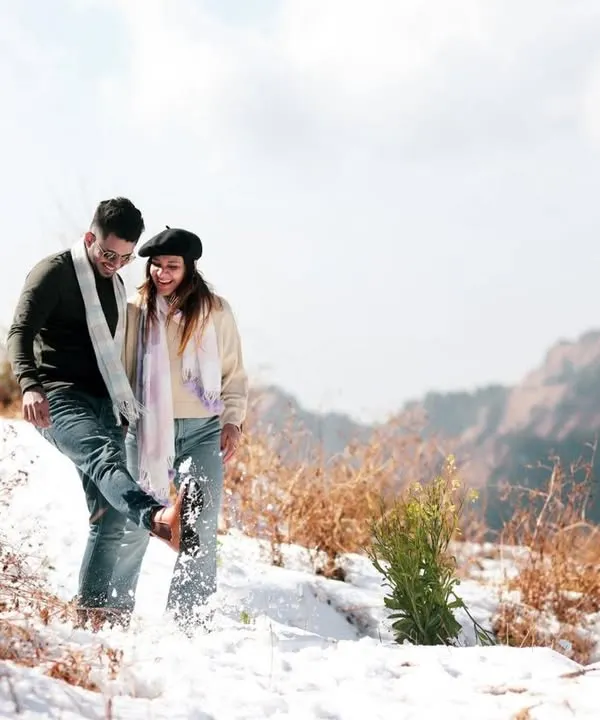 A playful moment captured in the snow. I believe pre-wedding shoots should be fun, and this candid shot of them kicking up snow shows their joyful and carefree connection amidst a stunning mountain landscape.