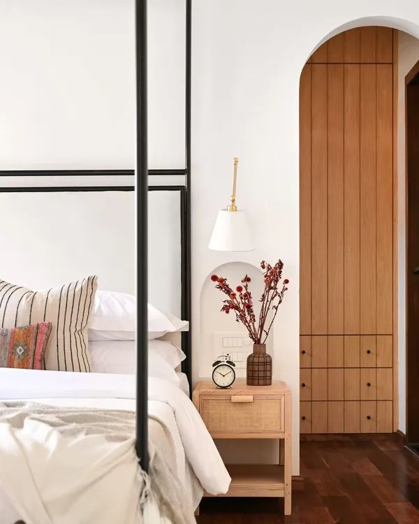 In this master bedroom, I added a wall to create a spacious walk-in closet, accessible through a beautiful arched doorway. The custom four-poster bed and rattan bedside tables were designed to fit the space perfectly, creating a serene and luxurious retreat.