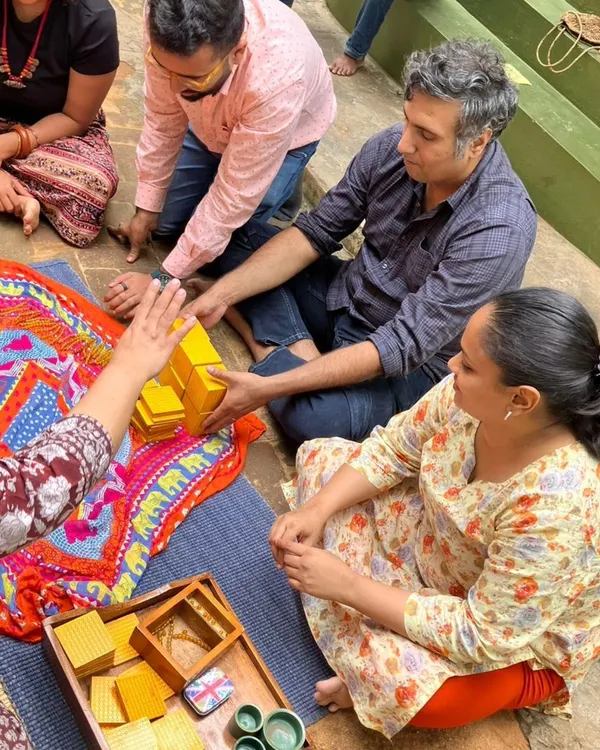 Parents work together with the Golden Bead material, which introduces the decimal system. This hands on experience demystifies how children learn complex mathematical concepts in a concrete, intuitive way.