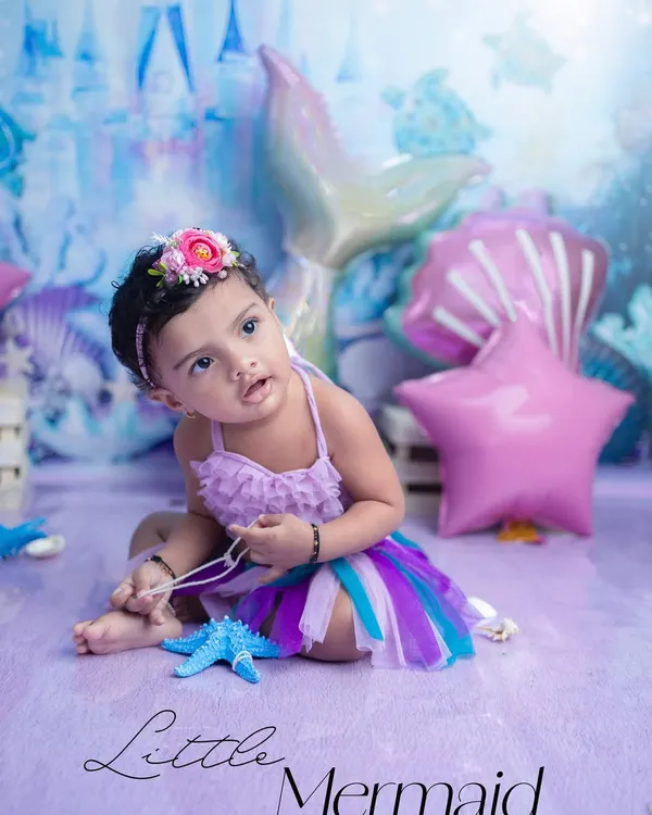 A magical 'Little Mermaid' session. The iridescent tail, seashell props, and underwater castle backdrop come together to create a truly enchanting world for this little one.