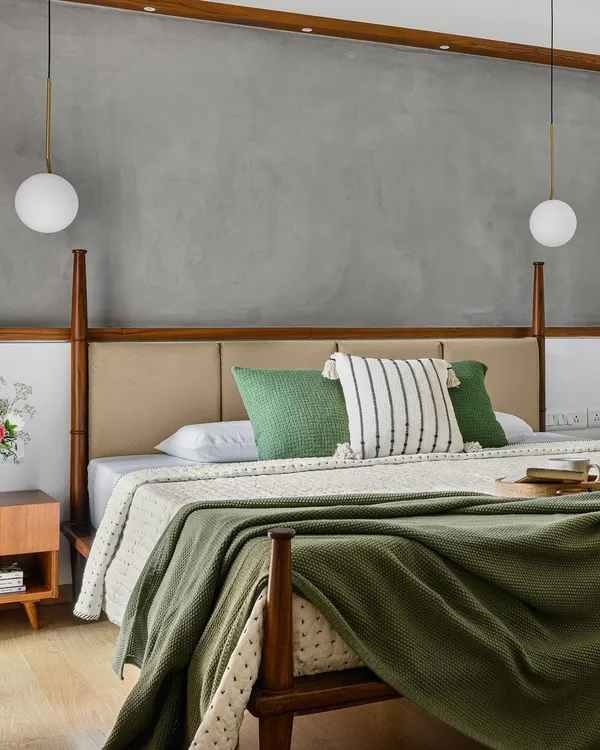 For the 'Poorna' primary room, we designed this half-poster bed to provide aesthetic appeal without obstructing the view of the TV, which is discreetly housed in the wardrobe. The concrete-finish texture wall adds a modern touch.