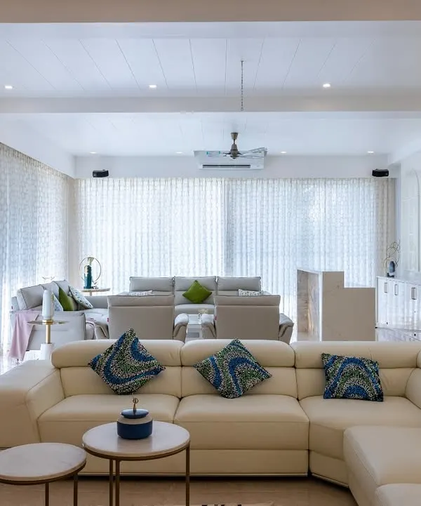 An expansive living area designed for seamless flow, where a cream leather sectional and patterned accent pillows create distinct zones for relaxation and conversation within a bright, open-concept layout.