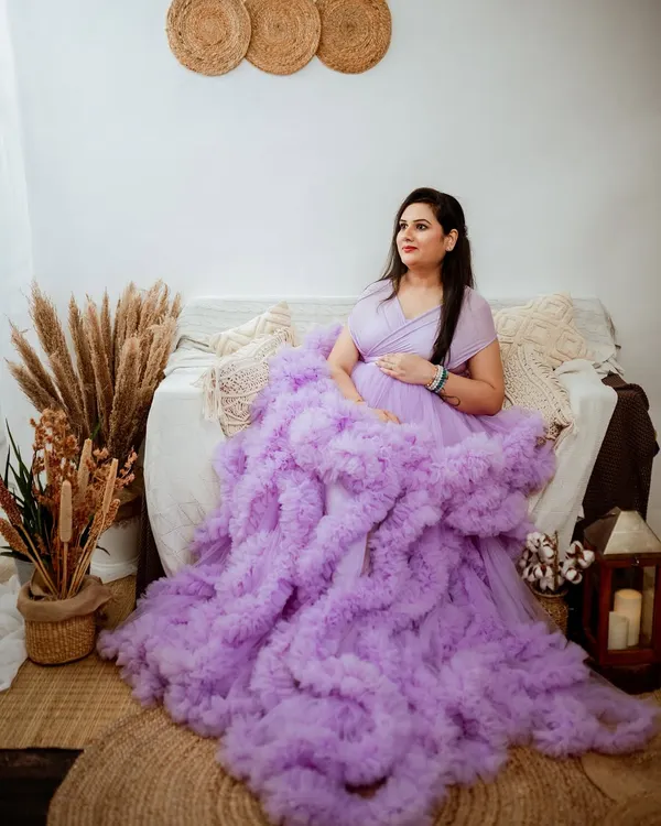 A classic portrait from a studio maternity session. The mom-to-be is wearing our popular lavender ruffled gown, seated in our comfortable and stylish boho-themed corner, complete with pampas grass and a vintage lantern.
