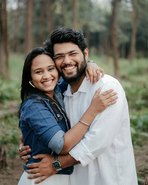 A bright, happy portrait of a couple hugging and smiling directly at the camera in a forest setting. This shot radiates pure joy and is perfect for capturing your fun-loving personalities.