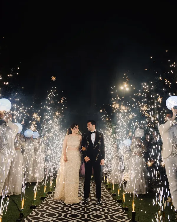 A spectacular entrance through a pathway of sparklers. This shot is full of energy and celebration, perfect for capturing the excitement of a sangeet or cocktail night.