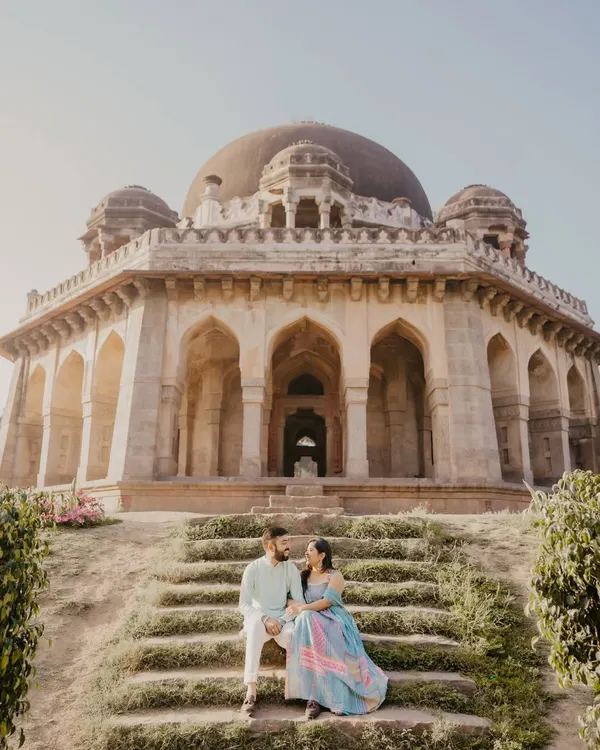 A majestic shot of a couple seated on the steps of a grand monument. This image perfectly captures the scale and romance of a heritage pre-wedding shoot in Delhi.