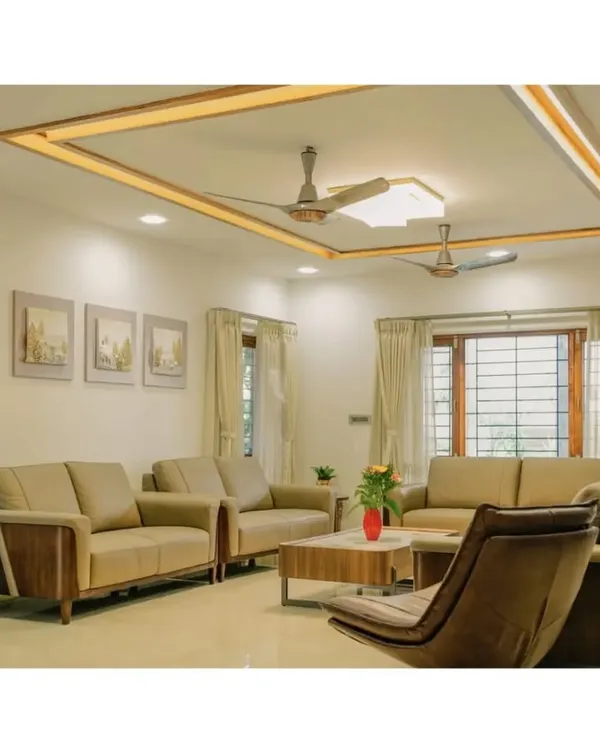 This view of the living room highlights the custom ceiling design with integrated cove lighting, which provides a soft, ambient glow. The layout is planned for conversation, with comfortable seating and large windows framed by simple curtains to maximize natural light.
