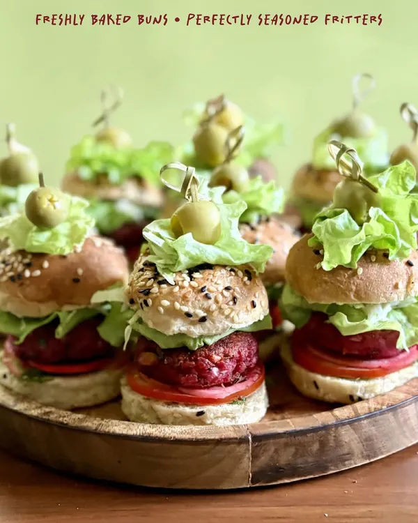 A closer look at my mini sliders, showcasing the freshly baked seeded buns, vibrant beetroot patty, crisp lettuce, and a juicy tomato slice. Each one is secured with an olive pick, ready to be enjoyed.